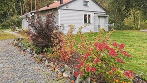 A two-story house with a red roof, surrounded by a well-maintained garden with various plants and flowers. - 2 bedroom nice home in Borrby (Borrby)
