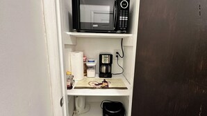 Ett litet pentry med mikrovågsugn, kaffebryggare och en papperskorg.