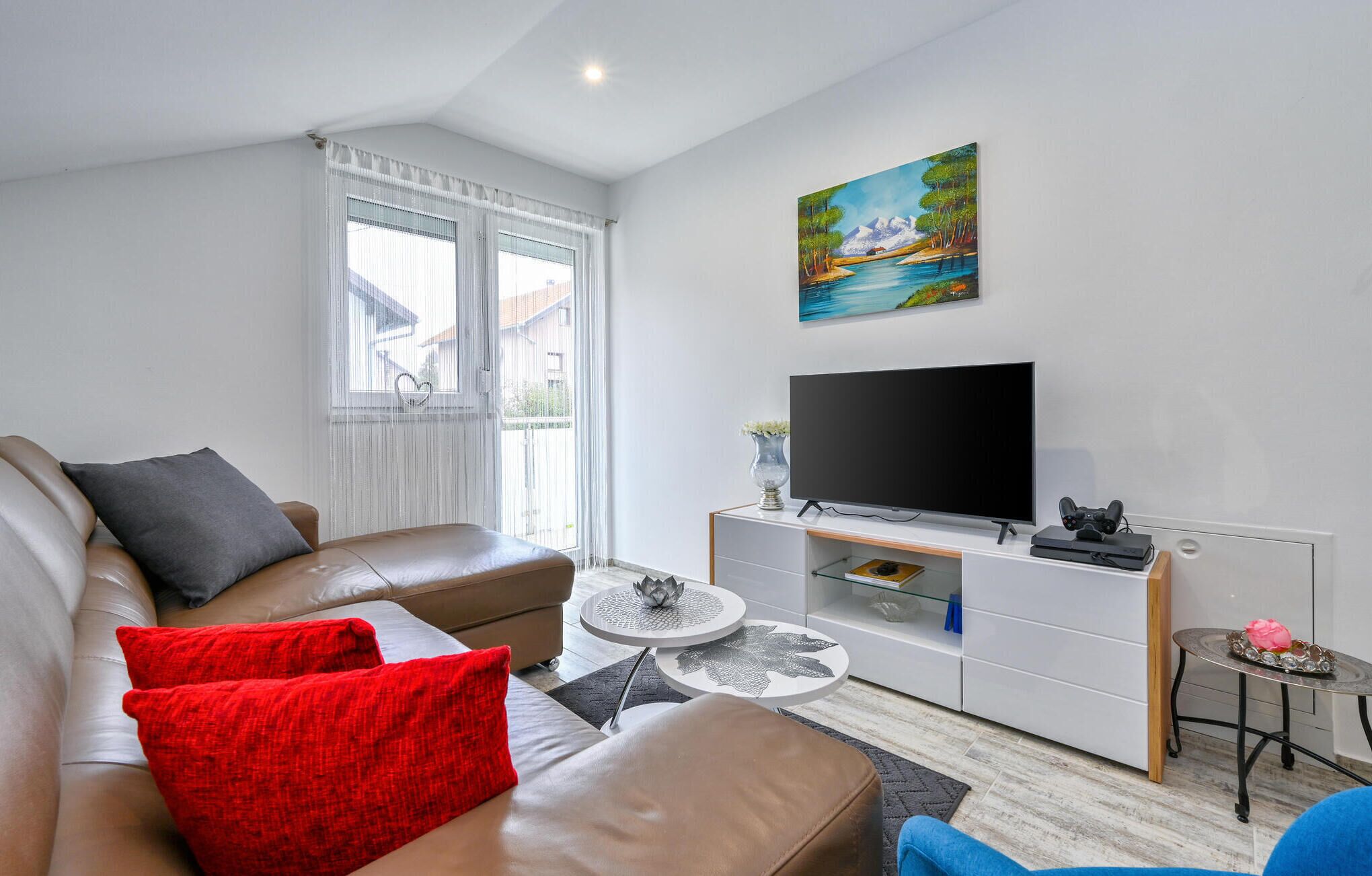 Een moderne woonkamer met een leren bank, een flatscreen televisie en een schilderij aan de muur.