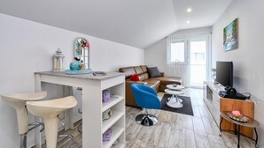 A modern living room with a sofa, a coffee table, a TV, and a dining area with a table and chairs. - Amazing home in Dugo Selo (Dugo Selo)