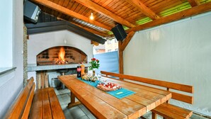 An outdoor patio with a wooden table, benches, a pizza, drinks, and a fire pit. - Amazing home in Dugo Selo (Dugo Selo)