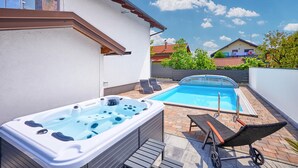 A backyard with a hot tub, a swimming pool, and two lounge chairs. - Amazing home in Dugo Selo (Dugo Selo)