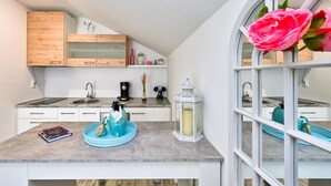 A modern kitchen with wooden cabinets, a marble countertop, a coffee machine, and a decorative lantern. - Amazing home in Dugo Selo (Dugo Selo)