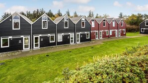 A row of modern, two-story houses with dark siding and white trim, featuring multiple garage doors and a well-maintained lawn. - Beautiful home in Nørre Nebel (Nørre Nebel)
