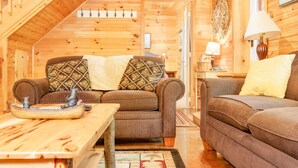 Interior acogedor de una cabaña de madera con dos sofás, una mesa de madera y una lámpara.