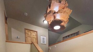 Een houten trap met een beer-muurschildering, een plafondlamp en een deur met een bordje erboven.