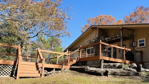 A wooden deck with a staircase leading to a building with a covered porch.