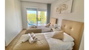 Ein Hotelzimmer mit zwei Betten, einem Balkon mit Blick auf den Pool und einem Bild an der Wand.