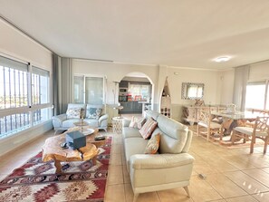 A spacious living area with a sofa, coffee table, and dining table.