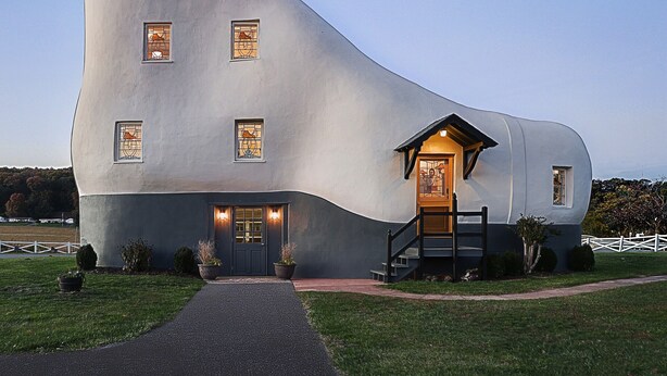 A unique, modern building with a curved facade, a central entrance with a staircase, and a small porch area.