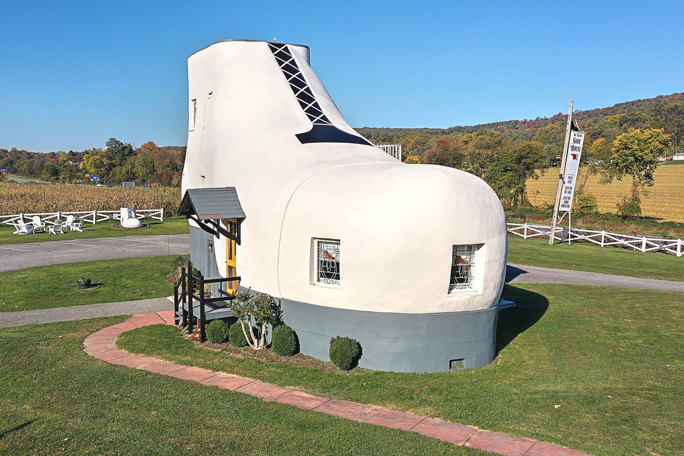 Un edificio moderno y singular con un diseño curvo, rodeado de un césped cuidado y una valla blanca.