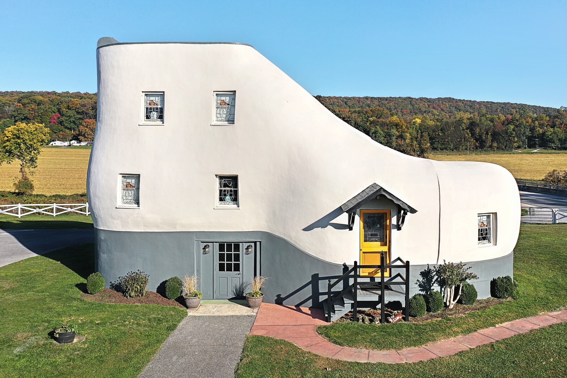Un bâtiment à l’architecture originale, doté d’une façade incurvée, d’une porte jaune et d’un petit porche avec une balustrade noire.