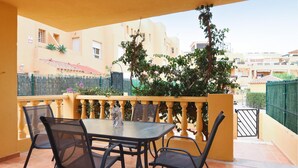 Un balcon avec une table et des chaises, une statue et une vue sur des bâtiments en arrière-plan.