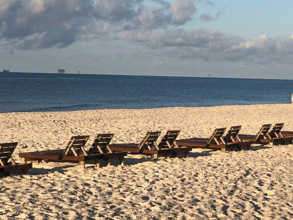 A beach with rows of wooden lounge chairs facing the ocean.