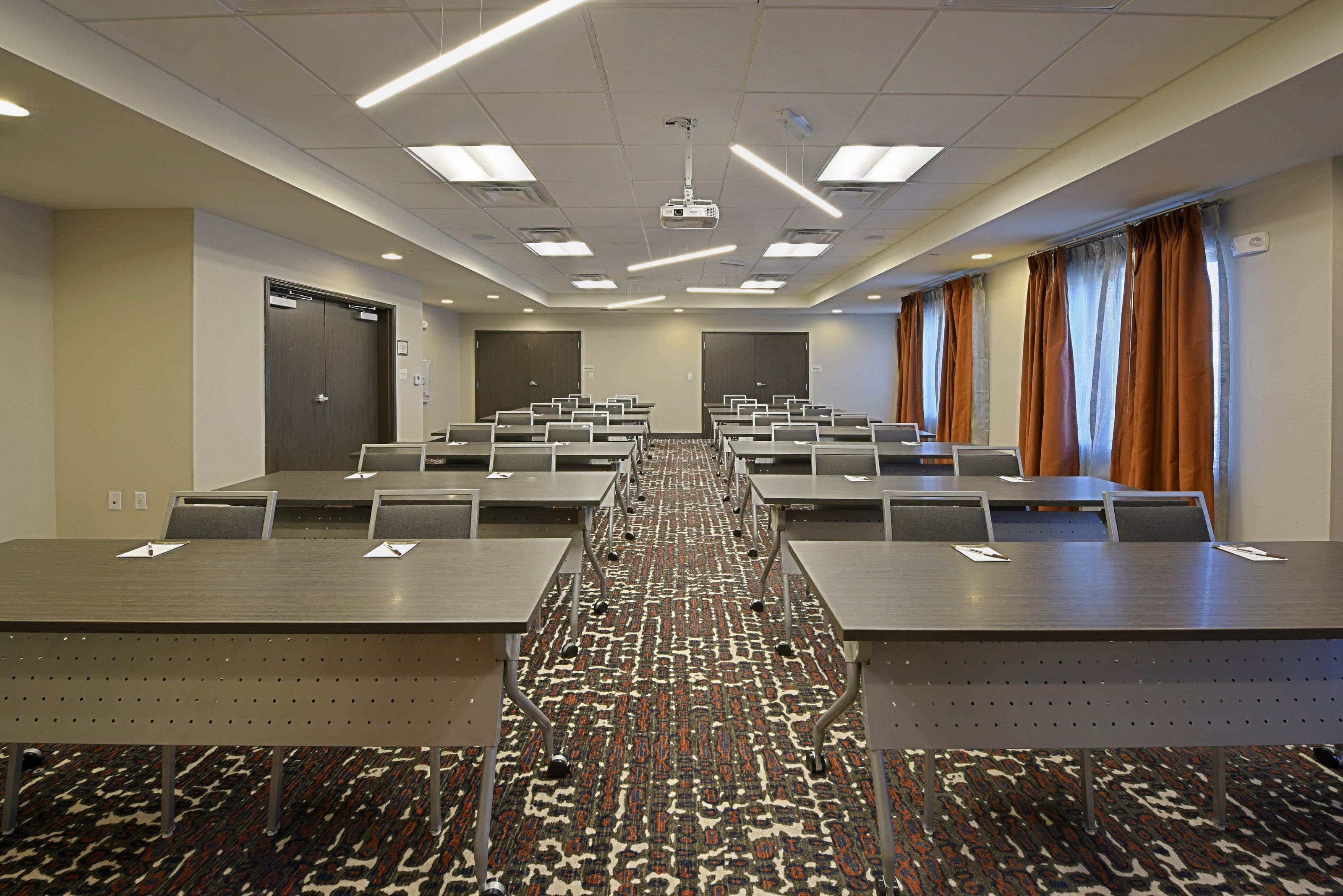 Een congreszaal met een lange tafel, meerdere stoelen en een vloerbedekking.