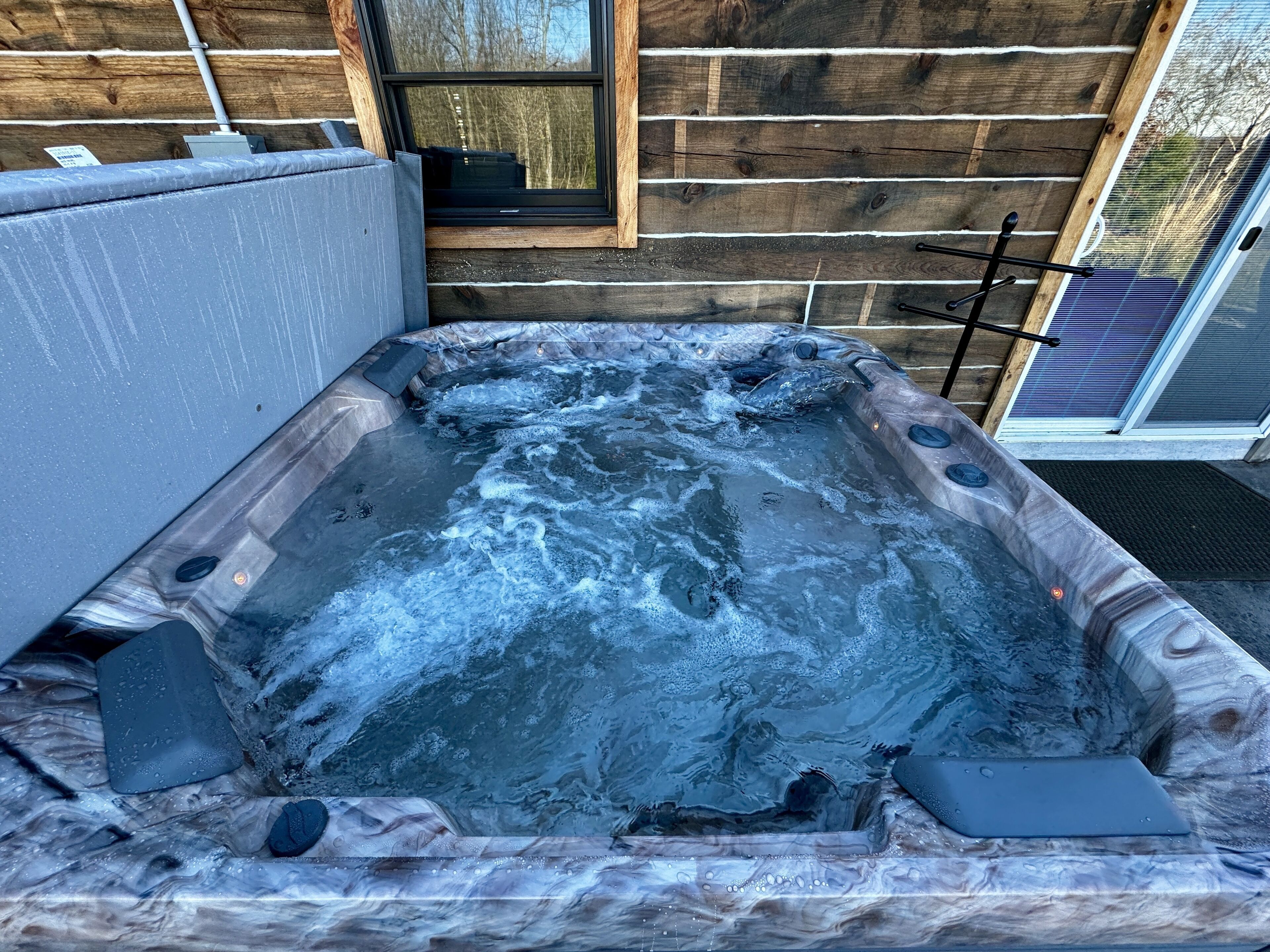 A hot tub with a wooden exterior, a window, and a door.