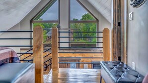 A high-ceilinged room with a sloped roof, large windows, and a view of the outdoors. - Rustic Hideaway Sleeps 4 HOT TUB (De Soto)