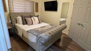 Une chambre à coucher avec un grand lit, un téléviseur à écran plat, une armoire et un luminaire au plafond.