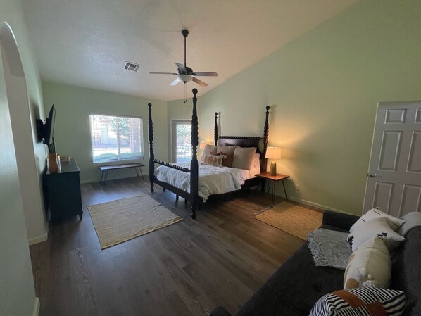A four-poster bed with a ceiling fan, a bedside table with a lamp, and a view of the outdoors through a window. - Golf Course Oasis w/private pool --- close to everything (Mesquite)