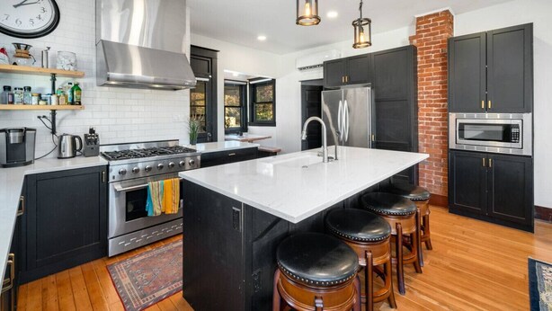 A modern kitchen with a central island, stainless steel appliances, and black cabinetry. - Mountain Manor in Sandy| HotTub |3KingBeds| MtHood (Sandy)