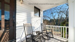 A wooden porch with two rocking chairs, a small window, and a white railing. - Mountain Manor in Sandy| HotTub |3KingBeds| MtHood (Sandy)
