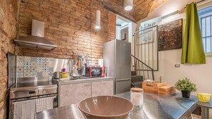 Una cocina con pared de ladrillo, electrodomésticos de acero inoxidable y una barra para colgar ollas.