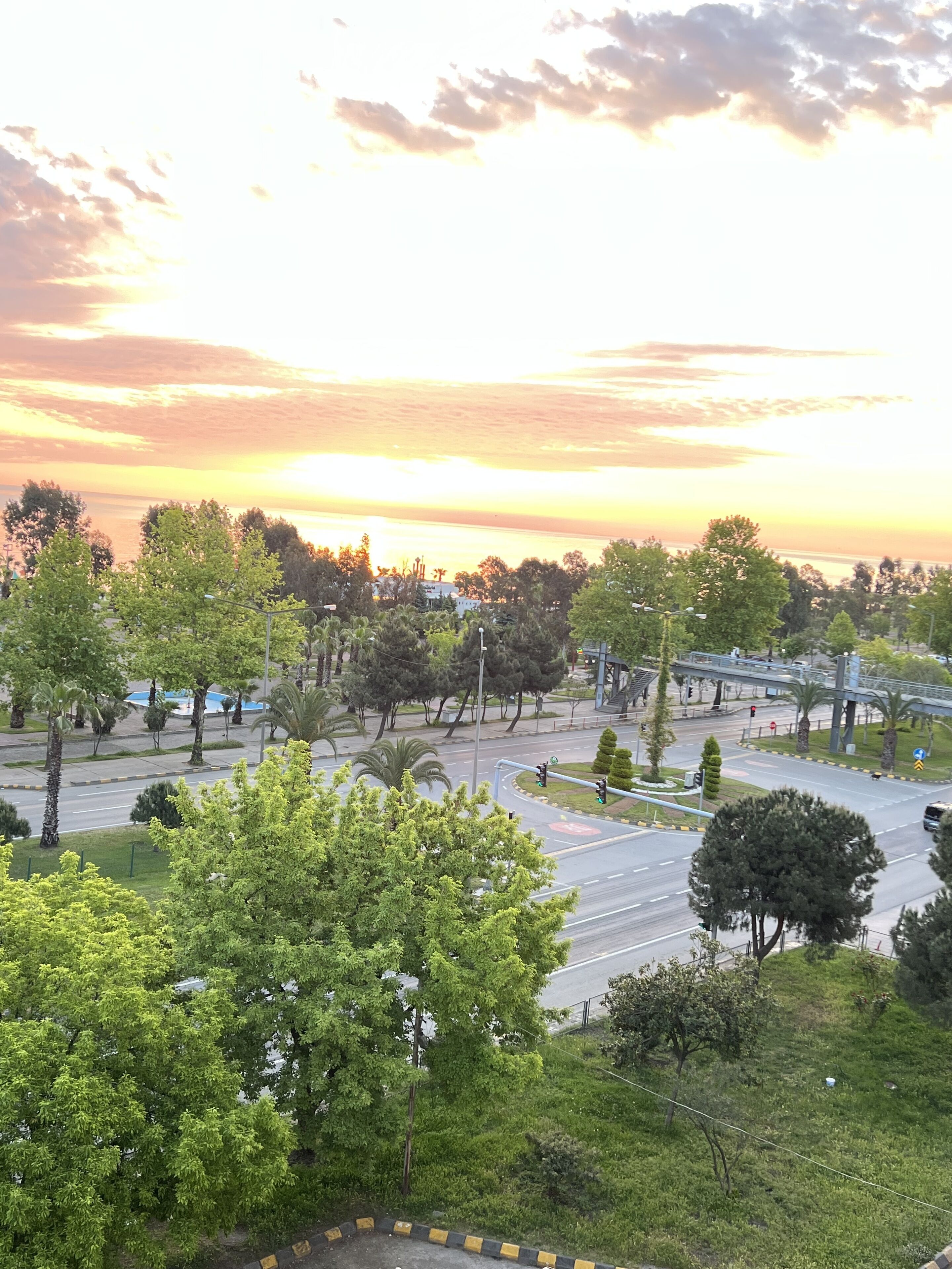 Eine Stadtlandschaft bei Sonnenuntergang, mit Straßen und Grünflächen.