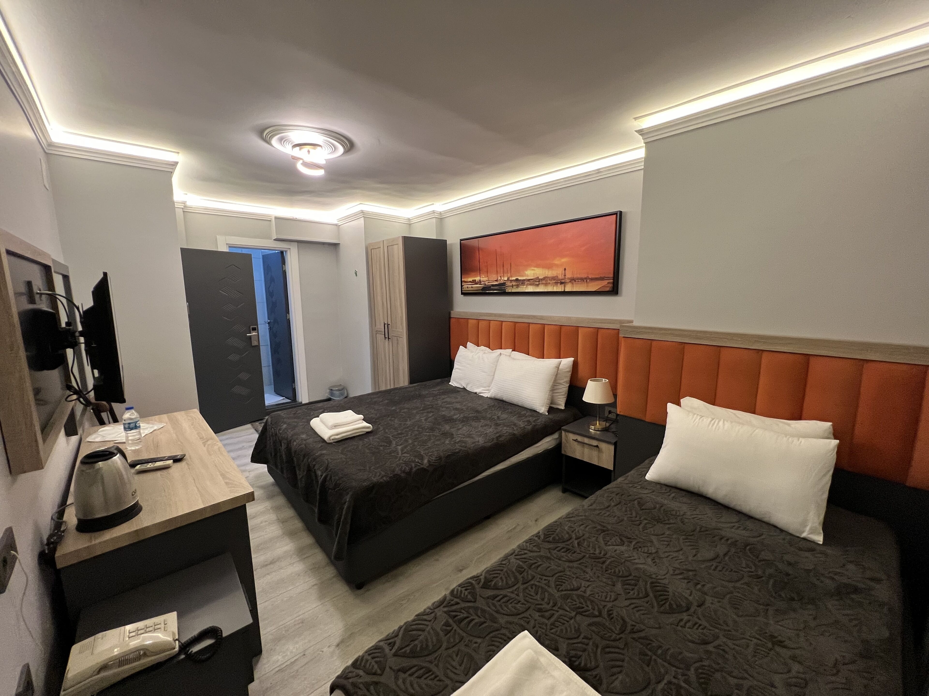 A hotel room with two beds, a desk, a TV, and a painting on the wall.