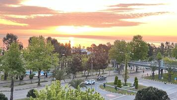 Une vue sur le coucher de soleil au-dessus d’une ville, avec ses rues, ses arbres et un pont.