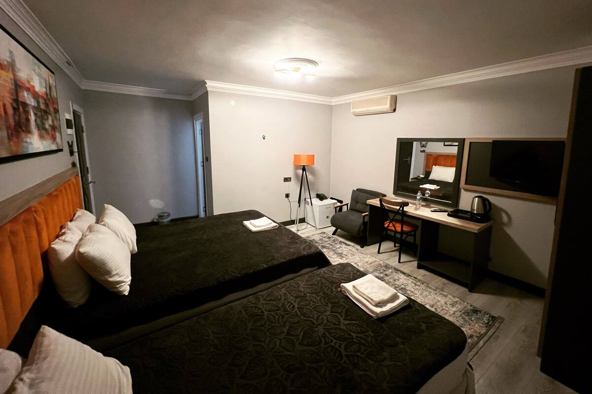 Une chambre d’hôtel avec deux lits, un bureau, une chaise, une télévision et une lampe de bureau.
