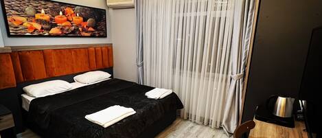 A hotel room with a bed, a wooden desk, a coffee maker, and a painting on the wall.