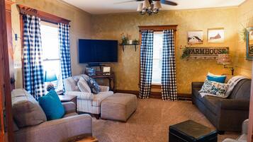 A living room with two sofas, a television, and a ceiling fan.