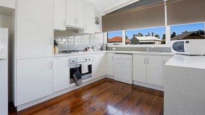 Une cuisine moderne avec des meubles blancs, une cuisinière, un four, un lave-vaisselle et un four à micro-ondes.