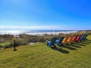 Eine Rasenfläche mit bunten Adirondack-Stühlen mit Blick auf Strand und Meer.