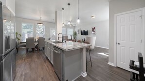 Una cocina moderna con una isla central, electrodomésticos integrados e iluminación colgante.