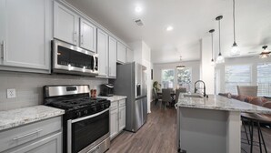 Una cocina moderna con electrodomésticos de acero inoxidable, armarios blancos y encimera de mármol.