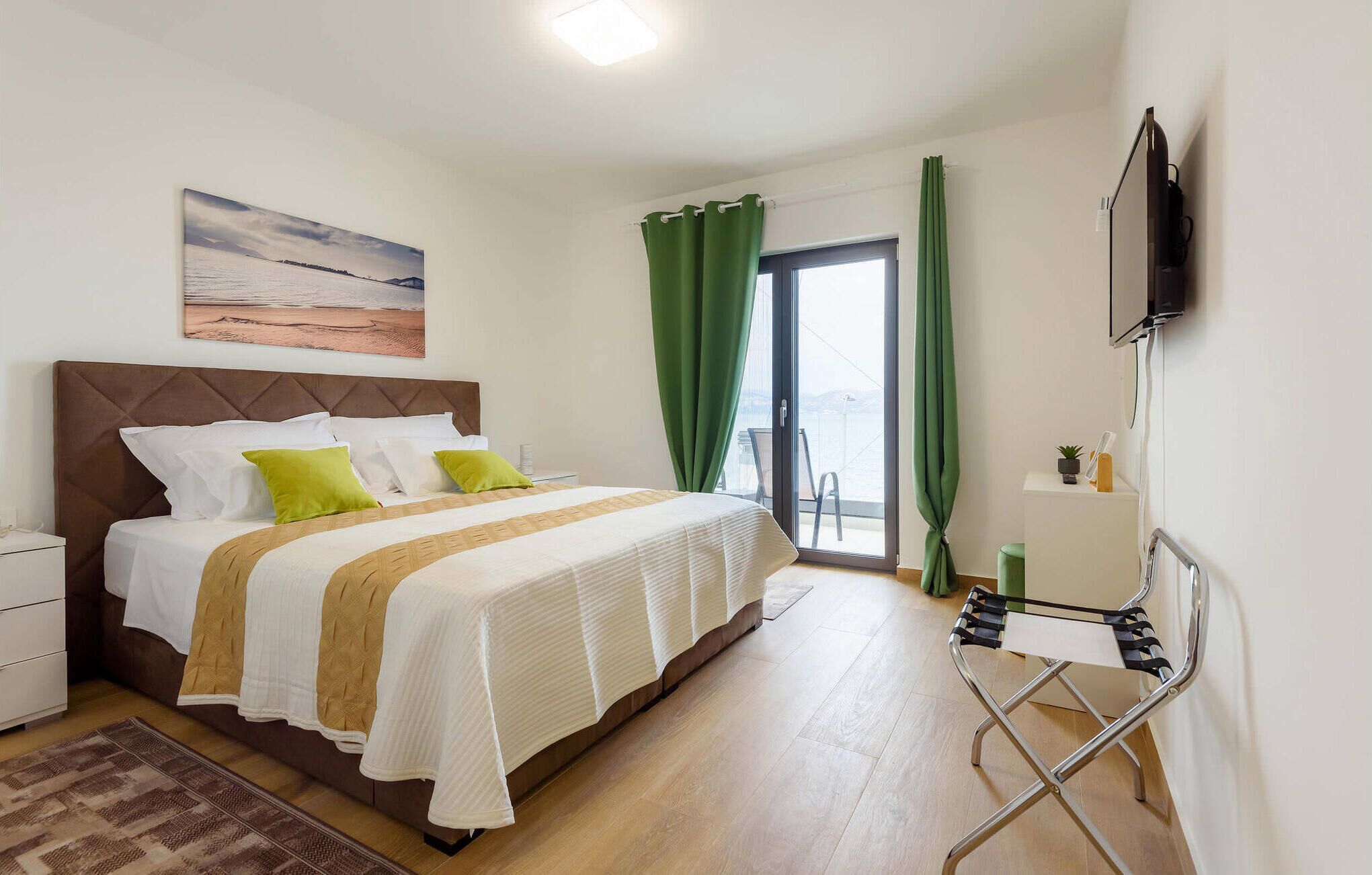 Un dormitorio con cama, mesita de noche, televisor y vistas al exterior.