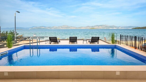 A pool with a clear view of the sea and mountains in the background. - Awesome home in Drace with sauna (Drace)
