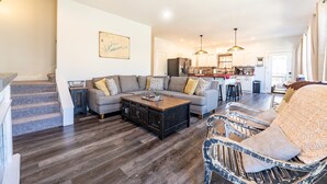 A spacious living room with a large sofa, a coffee table, and a dining area in the background.