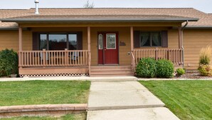 Ein Bungalow mit Veranda, einer roten Tür und einem kleinen Vorgarten.