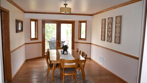 Ein Esszimmer mit Holztisch und Stühlen, einem Teppich und einer Deckenleuchte.
