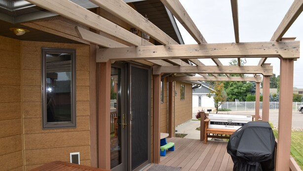 Eine Holzterrasse mit Grill, Tisch und Bank.