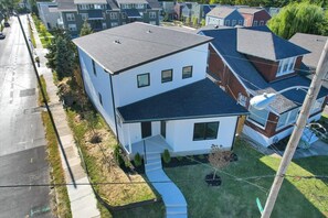 A modern two-story house with a sloped roof, a front porch, and a small front yard.
