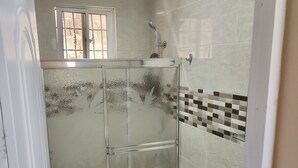 Un baño con ducha de vidrio, inodoro y lavamanos.