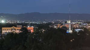 Un paisaje urbano al anochecer con edificios y una torre destacada.