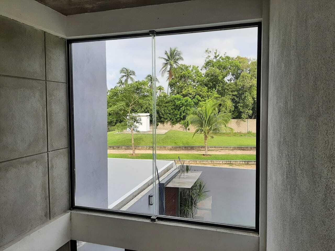 A room with a large window offering a view of a green landscape with trees and a road.