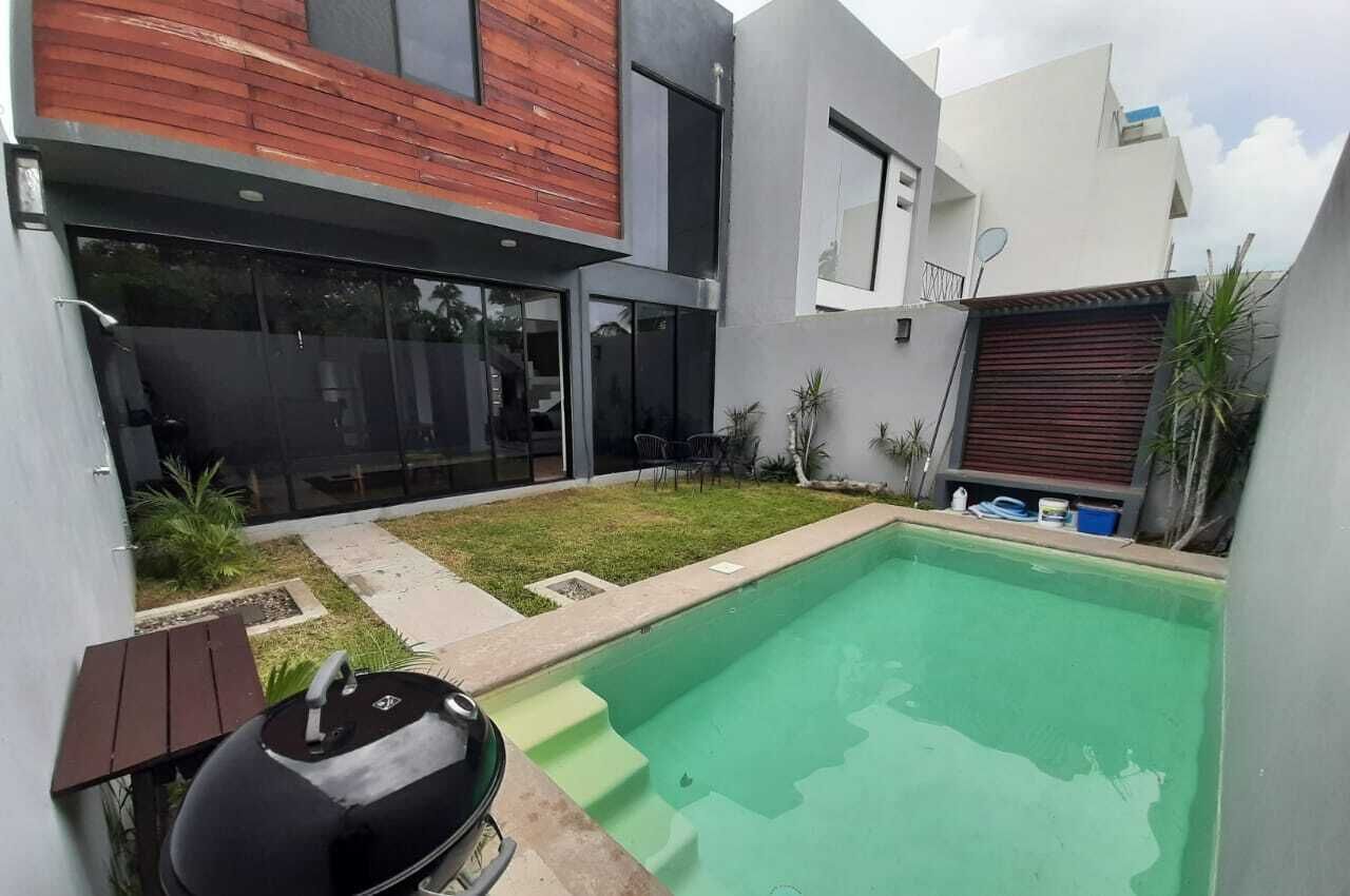 Ein modernes Haus mit Swimmingpool, Grill und Terrasse.