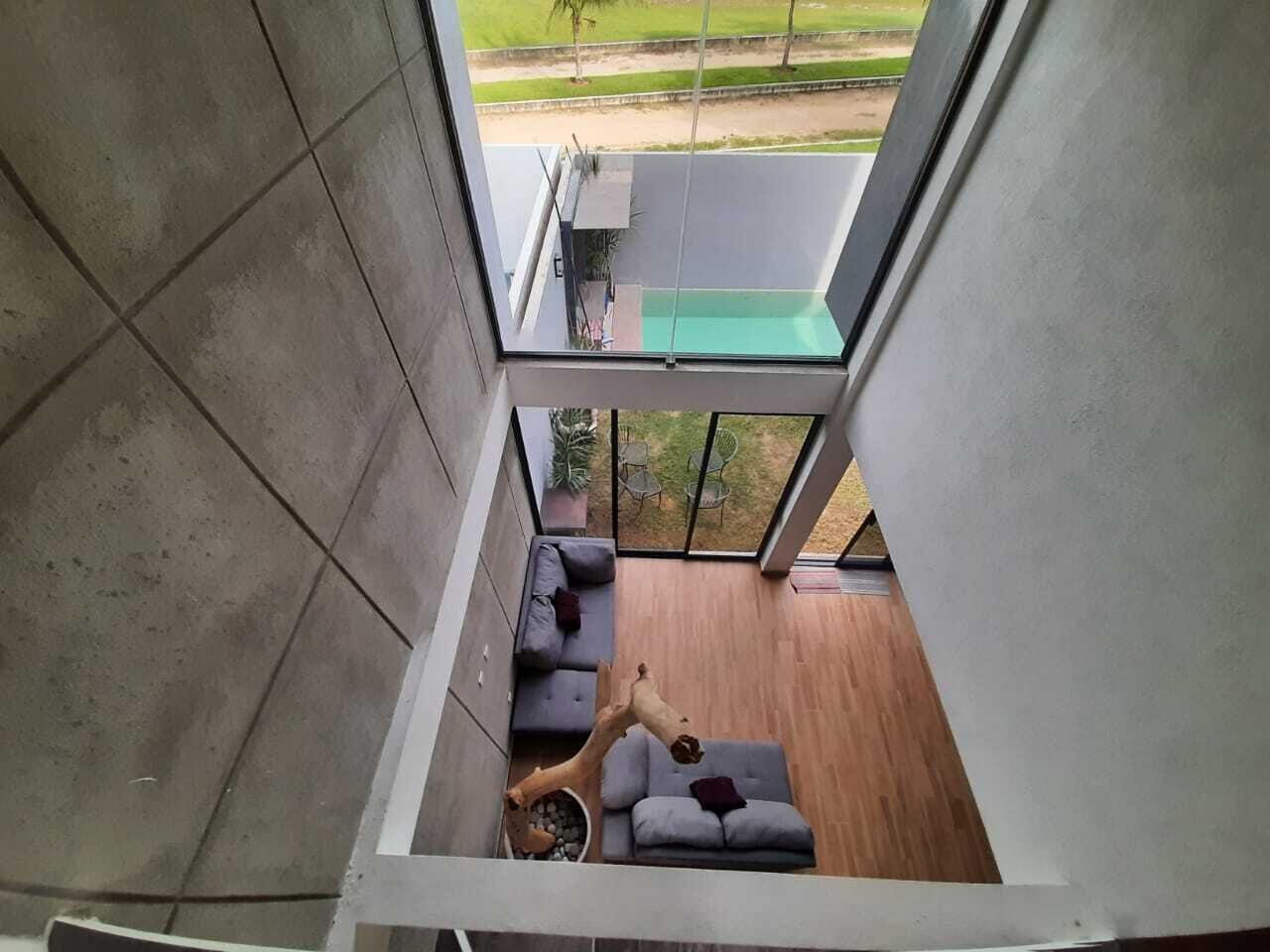 A modern interior with a wooden floor, grey sofa, and a small table with a bowl of fruit.