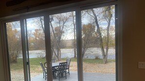 A room with a sliding glass door leading to an outdoor deck with a table and chairs. - Stillwater Riverfront Home, Close to the Beartooths, Fish from your door - Peace (Absarokee)