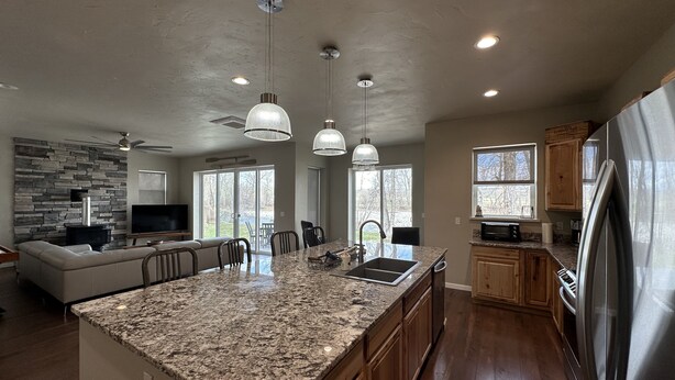 A spacious kitchen with granite countertops, wooden cabinets, and a large island. - Stillwater Riverfront Home, Close to the Beartooths, Fish from your door - Peace (Absarokee)